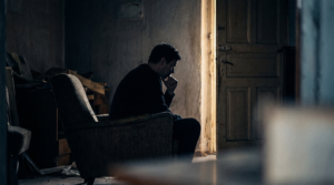 Person sitting in a dim room facing an open door with warm light, illustrating why good people stay in toxic situations